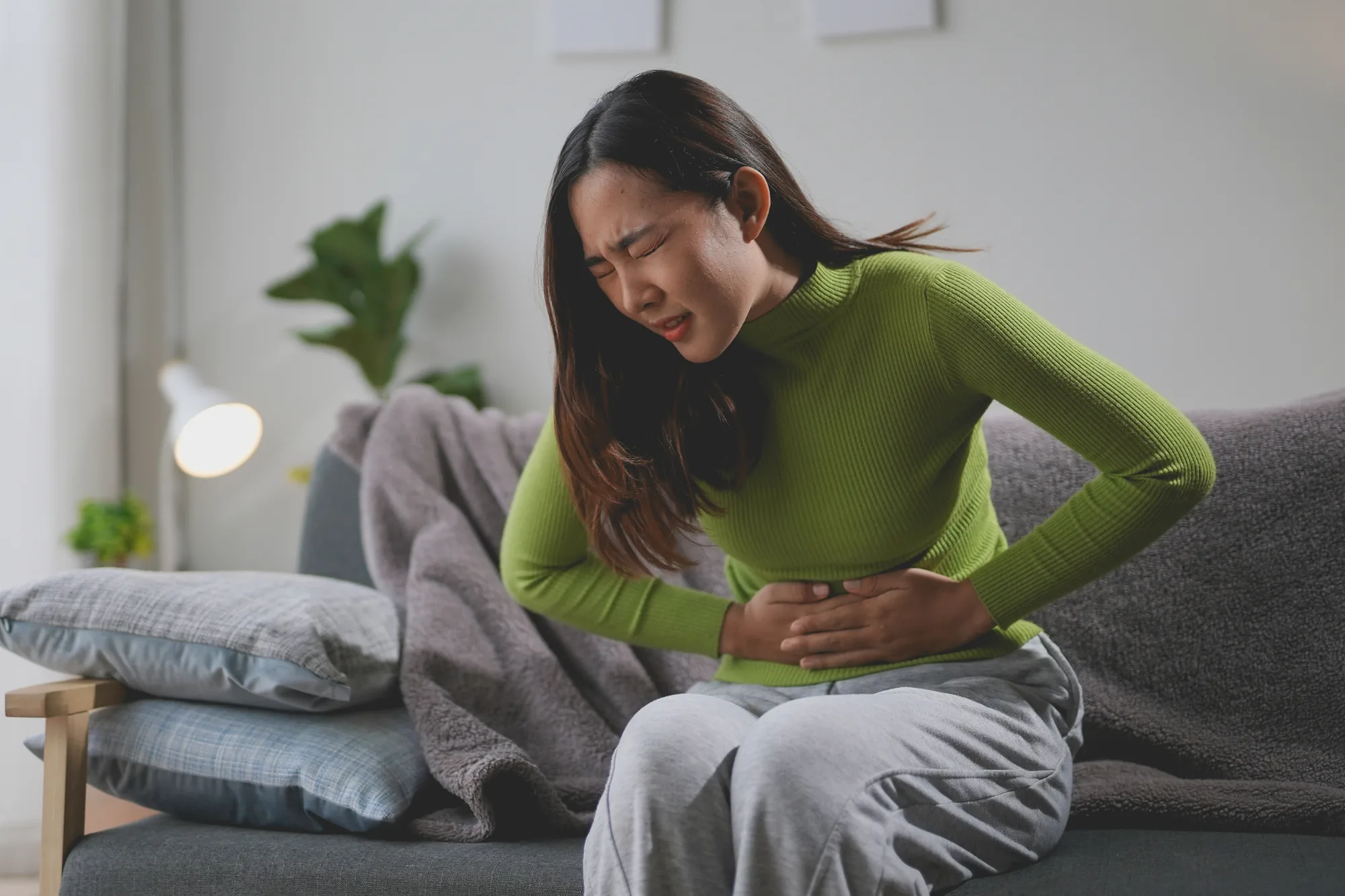 A woman sitting with both hands pressed to her stomach