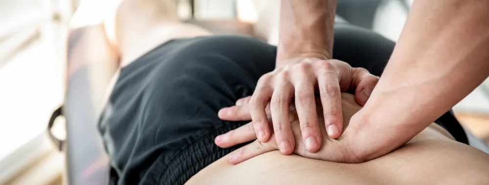 Hands applying sustained pressure over the lower back