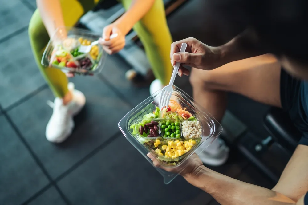 Two people with prepared salad bowls after training