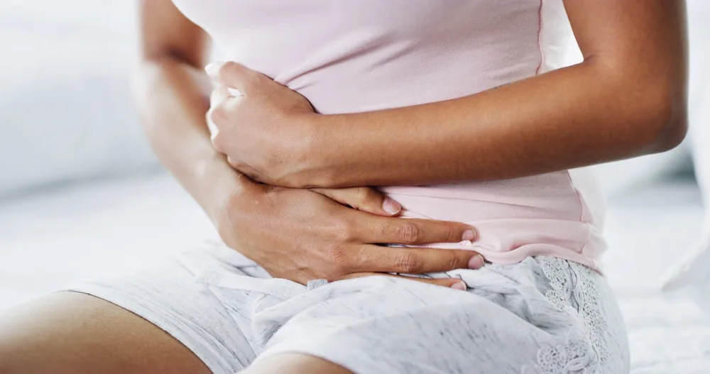 A woman resting both hands over her lower abdomen