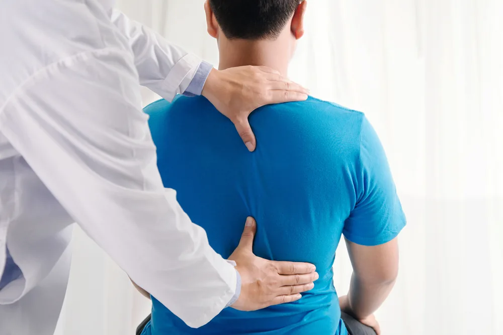 A clinician assessing a standing client's spine